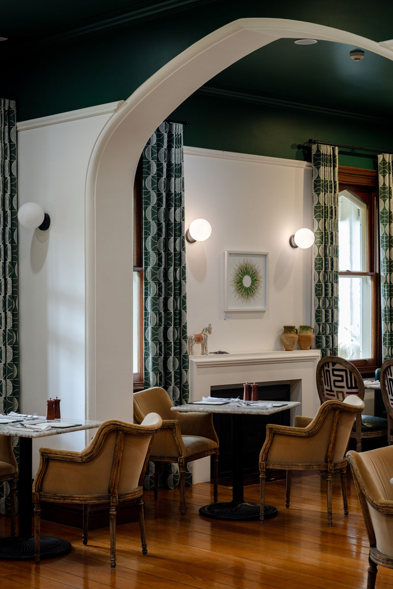 Cozy restaurant interior with vintage chairs and green patterned curtains